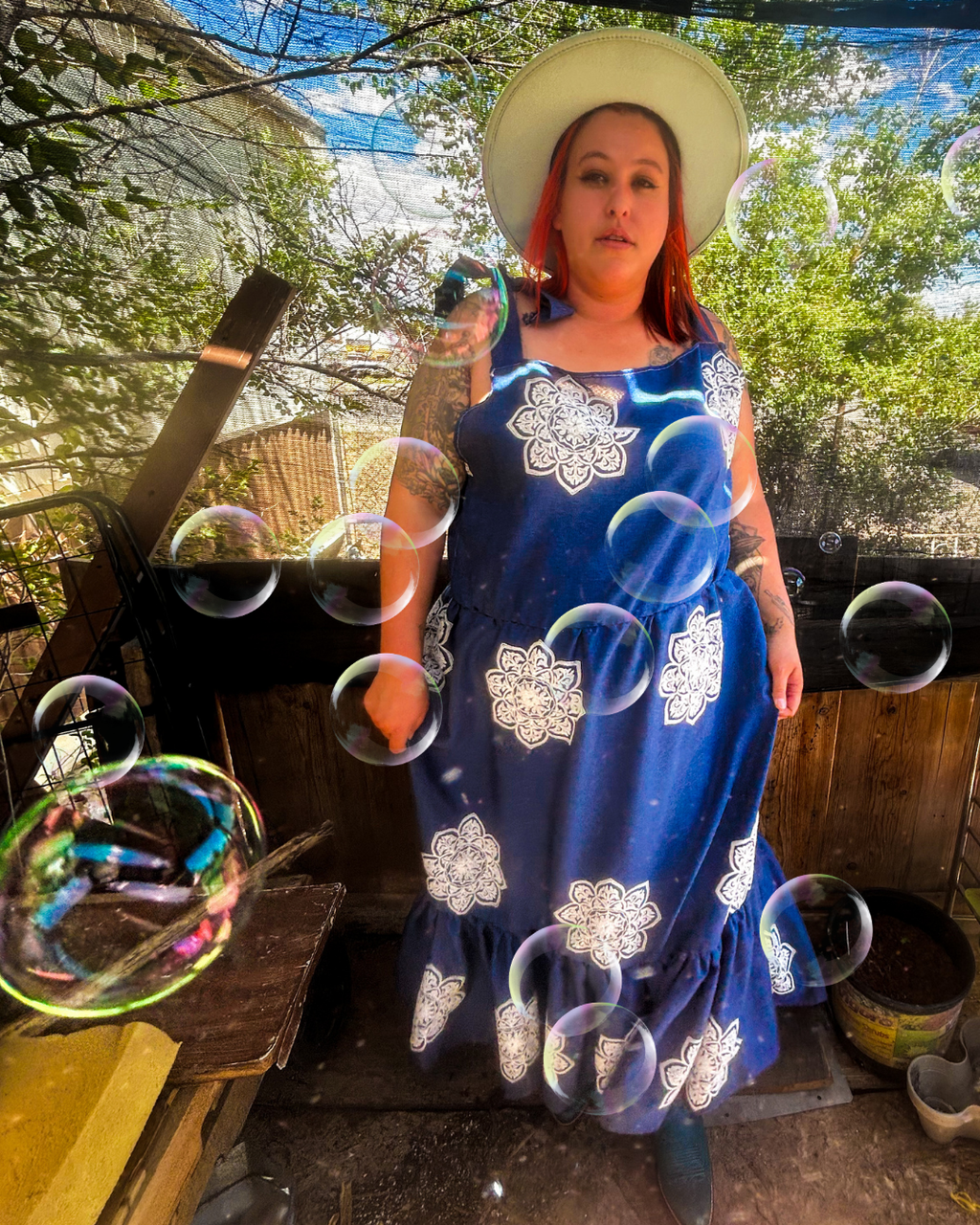 Woman in a blue dress with white patterns standing outdoors with bubbles