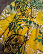 Golden Hour Tropics Two-Piece Set featuring a vibrant yellow skirt with tropical print details and flowy design.