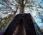 Cosmic Splash Flare Pants – One of a Kind Upcycled Statement Piece hanging on a tree with colorful panels.