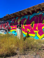Woman wearing Happy Daze Upcycled Bedsheet Skirt standing in front of colorful graffiti wall, showcasing funky women's clothing.