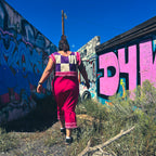 Woman walking in a vibrant pink Hot Mess Express Ruffle Skirt against colorful graffiti background.