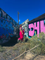 Woman wearing a Hot Mess Express Ruffle Skirt against colorful graffiti backdrop, showcasing funky women's clothing style.