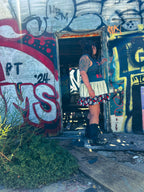 Woman wearing Just Chillin’ Killin’ Upcycled T-Shirt Dress in urban graffiti setting, showcasing unique women's clothing.