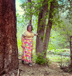 Woman wearing a colorful Cosmic Scarf Remix Skirt – One of a Kind Upcycled Statement Piece in a forest setting.