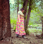 A woman wearing the Cosmic Scarf Remix Skirt – One of a Kind Upcycled Statement Piece amidst nature, showcasing colorful women's clothing.