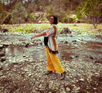 A woman wearing 🛸 Golden Mirage Flare Pants – One of a Kind Upcycled Statement Piece by the stream, showcasing unique women's clothing.