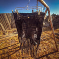 Midnight Outlaw Fringe Skirt hanging outdoors, showcasing bold hand-cut fringe and distressed denim details.