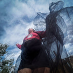A woman wearing the Betty in Paris Reworked Hoodie Dress with a flowing sheer skirt against a sky backdrop.