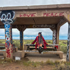 Woman wearing the Crimson Bloom Babydoll Dress – One-of-a-Kind Handmade Upcycled Statement Piece in graffiti setting.